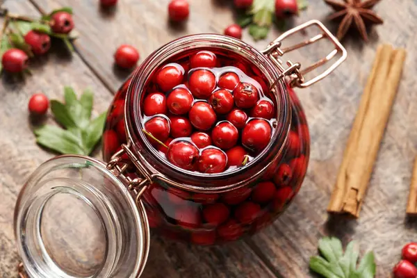 stock image Macerating wild hawthorn berries in red wine in a glass jar  - preparation of medicinal drink