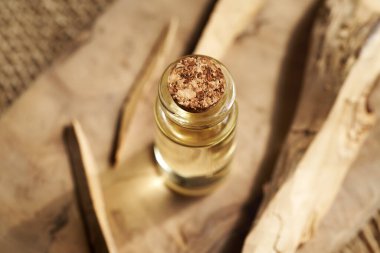 A transparent bottle of aromatherapy essential oil with white sandalwood on a table clipart