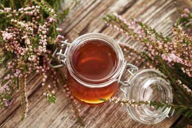 Cam kavanozda bitkisel şurup ve ormanda toplanan taze yabani kenevir çiçekleri.