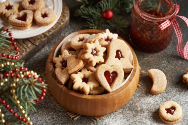Geleneksel ev yapımı Linzer Noel kurabiyeleri çilekli marmelatla doldurulmuş ve ahşap bir kasede şekerle tozlanmış.
