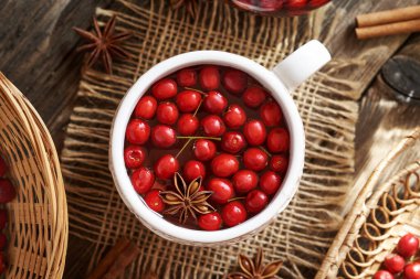 Beyaz bir fincan bitkisel çay, üzerinde taze dikenli meyveler, en iyi manzara.