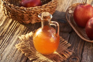 Bir sürahi elma sirkesi ve gün ışığında taze meyve.