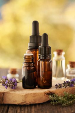 Sonbaharda açık havada taze lavanta çiçekleriyle birlikte üç kahverengi aromaterapi şişesi gerekli yağ. 