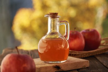 Sonbaharda açık bir masada taze meyveli elma sirkesi şişesi.