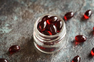 Kırmızı kril yağı hapları ya da cam kavanozdaki küreler, yakın plan.