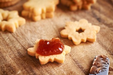 Yıldız şeklinde ev yapımı Linzer Noel kurabiyelerini çilekli marmelatla doldurmak