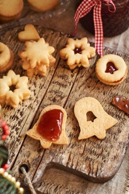 Ev yapımı Linzer Noel kurabiyelerini çilekli marmelatla dolduruyorum.