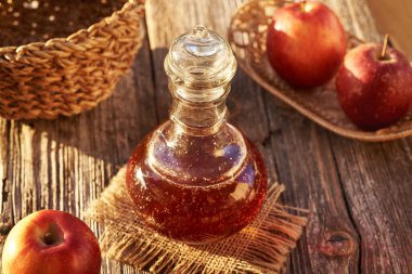 Bir şişe elma sirkesi ve açık havada taze meyve.