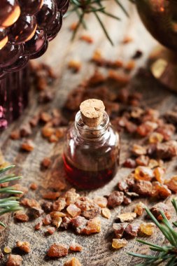 A bottle of myrrh essential oil and resin with a candle on a wooden table