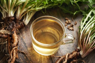 Bir fincan taze karahindiba kökü ve yapraklı bitki çayı.