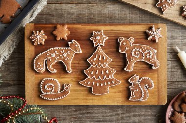 Beyaz kremayla süslenmiş orman hayvanları ve ağaçlar şeklinde ev yapımı zencefilli Noel kurabiyeleri.