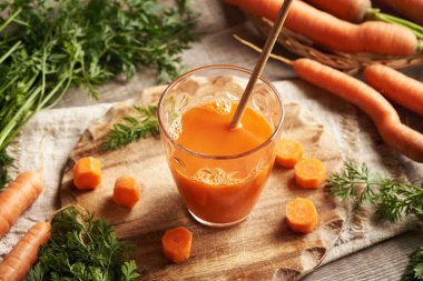 Masada ekolojik kağıt kamışla birlikte bir bardak taze havuç suyu. Sıfır atık.