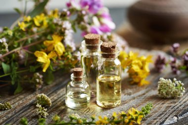 Renkli yaz çiçekleriyle birlikte birkaç şişe aromaterapi yağı.