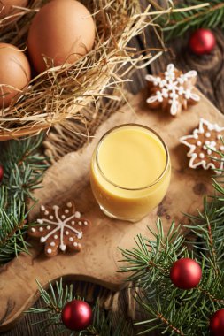 Bir bardak Eiecognac, taze yumurta ve Noel süslemesi.