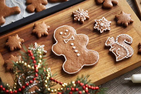 Decorating man and animal shaped gingerbread Christmas cookies with white icing