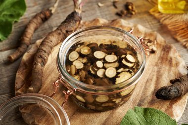 Cam bir kavanozda taze dilimlenmiş dulavrat kökü bitkisel tentürlerin hazırlanması.