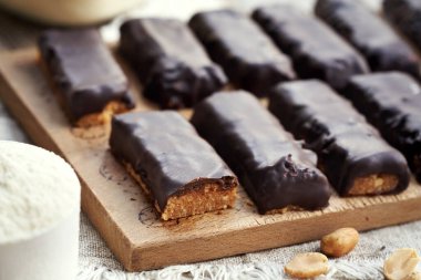 Süt tozu ve çikolata kaplı fıstık ezmesinden yapılmış ev yapımı pişirilmemiş sağlıklı barlar.