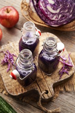 Masada taze elma ve salatalık ile üç şişe mor lahana suyu.