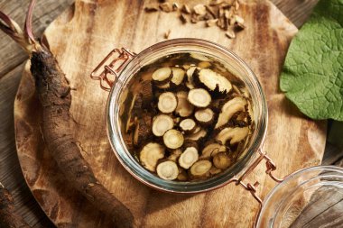 Dilimlenmiş taze dulavrat kökü alkolün içinde. Ev yapımı bitkisel tentürlerin hazırlanması.