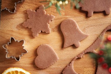 Shapes cut out from raw pastry dough - making homemade gingerbread Christmas cookies clipart