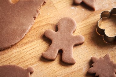 Man shape cut out from raw pastry dough - preparation of homemade gingerbread Christmas cookies on a table clipart