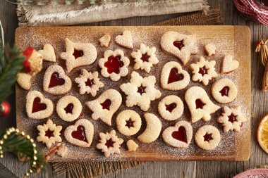 Çilek reçeli ile doldurulmuş ev yapımı Linzer Noel kurabiyeleri ve köknar ağacı dallarıyla tahtadan yapılmış şeker tozları.