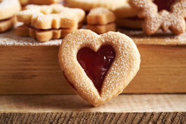 Ayakta duran kalp şeklindeki Linzer Noel kurabiyeleri çilek reçeli ve şekerle kaplanmış, yakın plan.