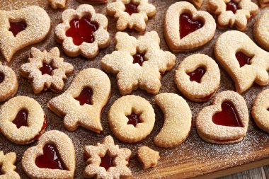 Geleneksel Linzer Noel kurabiyeleri çilekli marmelatla dolu ve tahta tahtada şekerle tozlanmış.