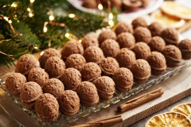 Çam ağacı dalları ve süslemeleri olan cam bir tabakta kremayla doldurulmuş fındık şeklinde ev yapımı Noel kurabiyeleri.