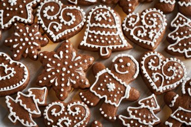 Ev yapımı zencefilli Noel kurabiyesi üzerine beyaz kremayla süslenmiş kağıt parşömen kağıdı, üst manzara.