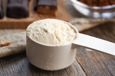 Arka planda ev yapımı sağlıklı çikolata ve çiğ kakao içeren bir kepçe süt tozu.