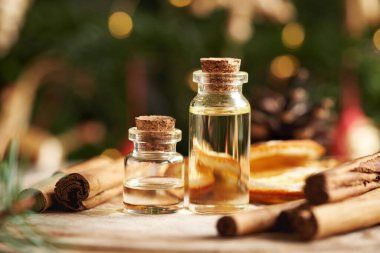 İki şeffaf aromaterapi şişesi Seylan tarçın çubukları ve Noel süslemeleri ile gerekli yağ