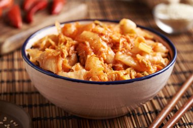 Kırmızı biber, susam tohumu ve Asya yemek çubuklarıyla bir masada mayalanmış kimçi.