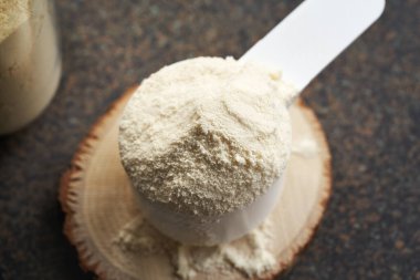 Plastik ölçü kabında beyaz protein tozu, yakın plan.