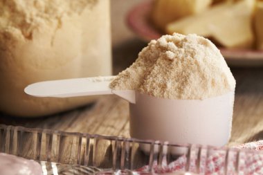 Beyaz plastik ölçü kabında beyaz protein tozu
