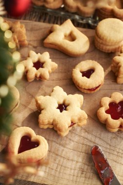 Geleneksel Linzer Noel kurabiyeleri ahşap bir masada kırmızı marmelatla dolu.