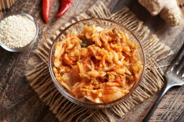 Kırmızı biberli, susamlı ve zencefilli cam bir kasede mayalanmış kimchi.