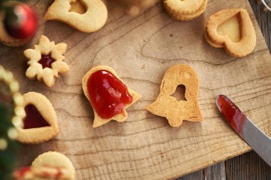 Ev yapımı Linzer Noel kurabiyelerini kırmızı marmelatla doldurmak.