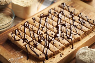 Süt tozu, yulaf ezmesi, susam ağacı ve akçaağaç şurubuyla süslenmiş ev yapımı atıştırmalık barlar.