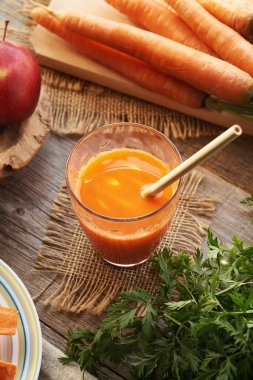 Tahta bir masada ekolojik bambu kamışlı bir bardak taze havuç suyu.