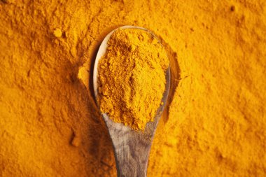 Ahşap bir kaşıkta zemin zerdeçal kökü tozu, üst manzara.