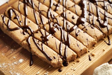 Süt tozu, yulaf ezmesi, akçaağaç pekmezi, tarçın ve fındık ezmesinden yapılmış ev yapımı atıştırmalıklar, koyu çikolatayla süslenmiş.