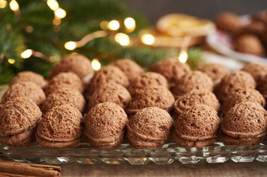 Ev yapımı fındık şekilli Noel kurabiyeleri kakao kreması ile doldurulmuş köknar ağacı dalları ve arka planda peri ışıkları.