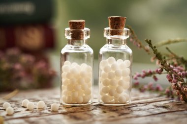 İki şişe beyaz homeopatik hap ya da kurumuş ot ve kitaplarla dolu küreler.