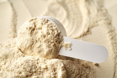 Bir ölçü kabında beyaz protein tozu, yakın çekim.