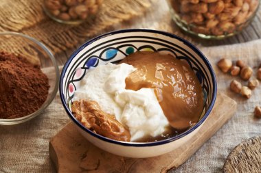 Yunan yoğurdu, fındık ezmesi ve akçaağaç şurubu. Ev yapımı sağlıklı tatlılar için malzemeler.