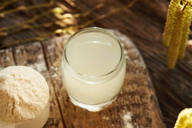 Bir kepçe beyaz protein tozuyla cam bardakta taze doğal süt.