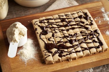 Tahta kesme tahtasına siyah çikolata ile süslenmiş ev yapımı beyaz protein çubukları.