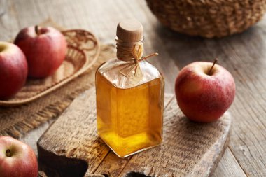 Elma şarabı sirkesi. Ahşap bir masada cam bir şişede.