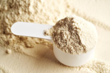 Beyaz bir ölçü kabında beyaz protein tozu, yakın çekim